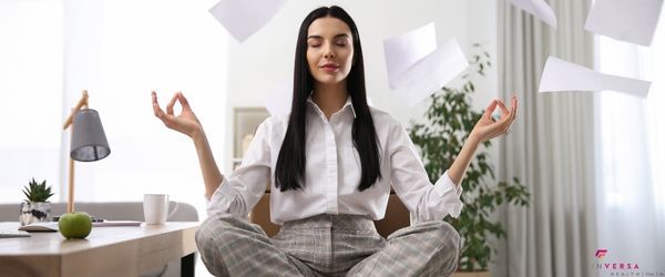 woman meditating with eyes closed while papers are flying in the air