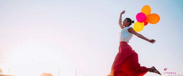 woman with balloons and red skirt jumping for joy in a sunny field