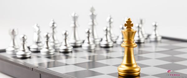 gold king chess piece in the foreground of a chest board with silver pieces in the background